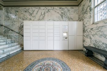 A white cabinet with a door is in the middle of a marble floor.